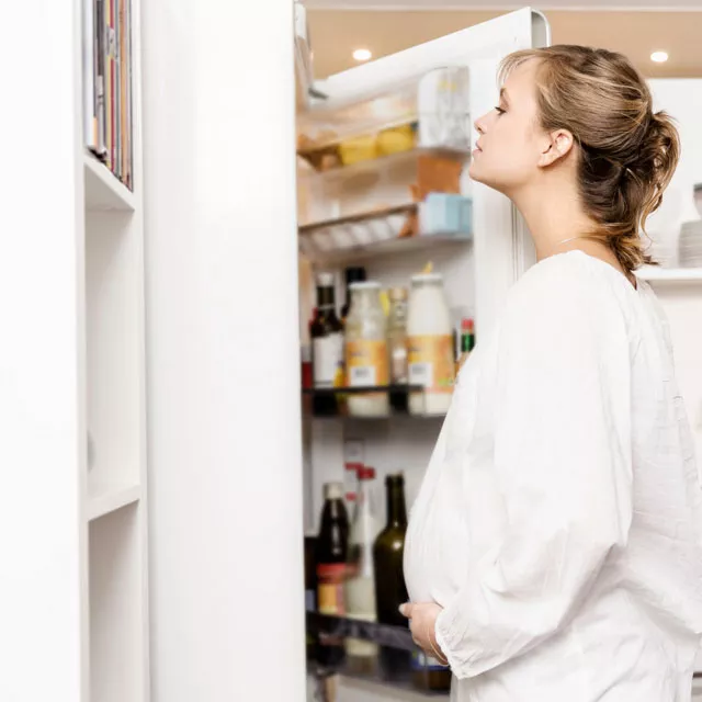 pregnant woman looking in fridge