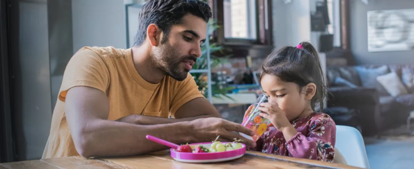 father helping daughter drink water at lunch